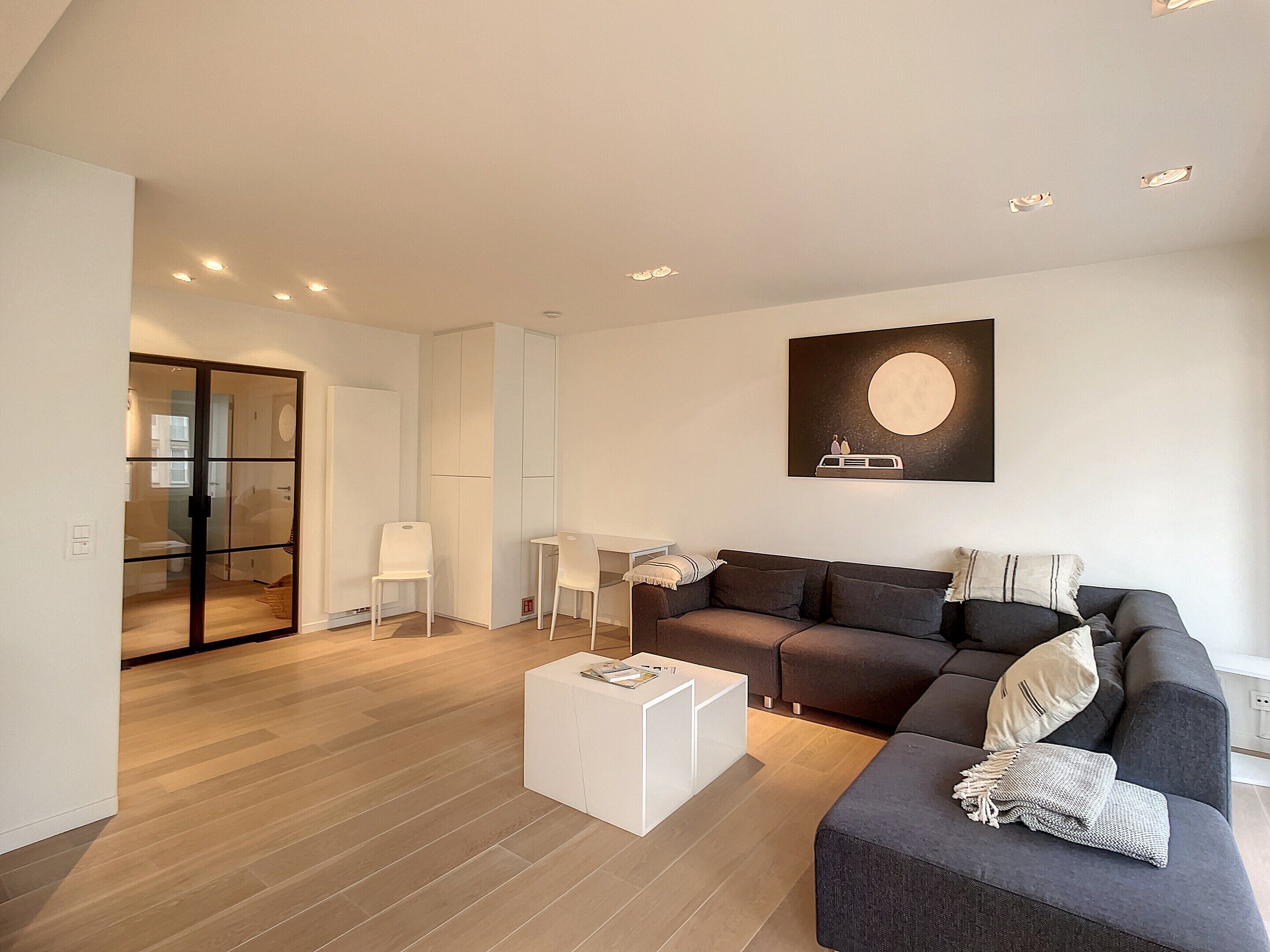 Een moderne woonkamer met een bank, een salontafel en een schilderij aan de muur.