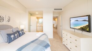 A bedroom with a bed, a TV, and a view of the sea.