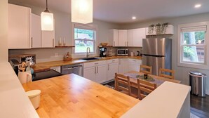 A modern kitchen with white cabinets, a wooden countertop, stainless steel appliances, and pendant lighting. - Bright, Spotless Cottage Near Bethel Woods (Highland)