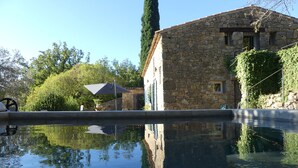 A stone building with a pool reflecting its surroundings.