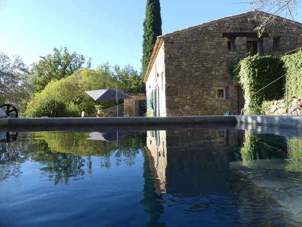 A stone building with a pool reflecting its surroundings.