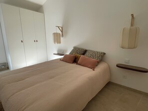 Una camera da letto con un letto, cuscini, una mensola a parete e un armadio.