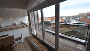 Een balkon met grote ramen met uitzicht op een woonwijk.