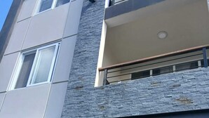 A modern building with multiple windows, a stone facade, and a balcony. - Cypress Suites (Roseau)