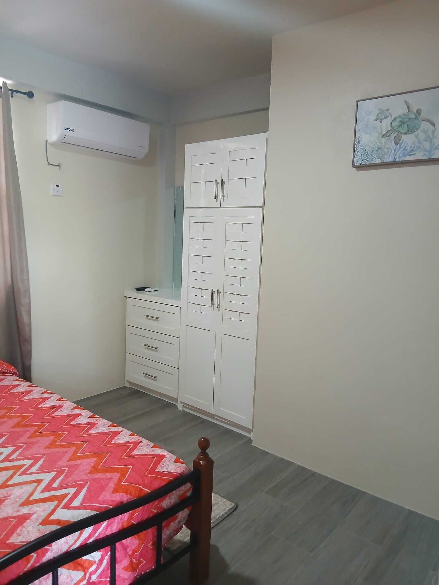 Un dormitorio con cama, armario y aire acondicionado.