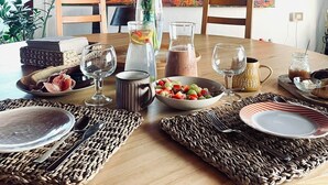 A dining table set with various dishes, a vase of flowers, and a colorful abstract painting in the background. - Casa Natura 23 (San Bartolomé)
