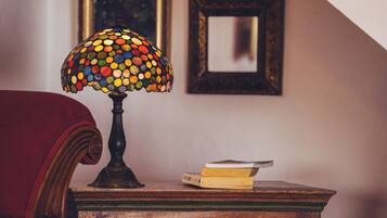 Une lampe avec un abat-jour en mosaïque, une pile de livres et un tableau encadré, le tout posé sur une surface en bois.