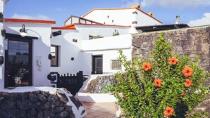 Un bâtiment blanc avec un mur en pierre et une entrée carrelée.