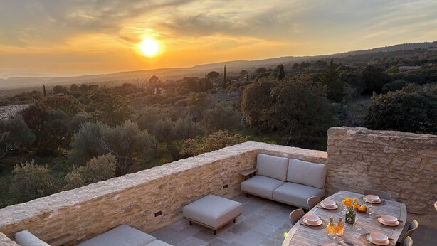 A terrace with stone walls, outdoor seating, and a table set for dining with a sunset view. - Soothing Provençale 3-bedroom house with WiFi in picturesque Gordes (Gordes)