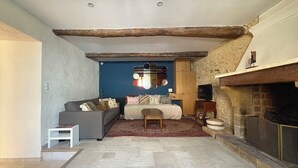 A cozy living room with a stone fireplace, a sofa, a small table, and a blue accent wall. - Soothing Provençale 3-bedroom house with WiFi in picturesque Gordes (Gordes)