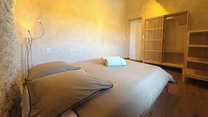 A bedroom with a bed, a wooden wardrobe, and a door. - Soothing Provençale 3-bedroom house with WiFi in picturesque Gordes (Gordes)
