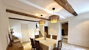 A dining area with a round table, six chairs, and two hanging light fixtures. - Soothing Provençale 3-bedroom house with WiFi in picturesque Gordes (Gordes)