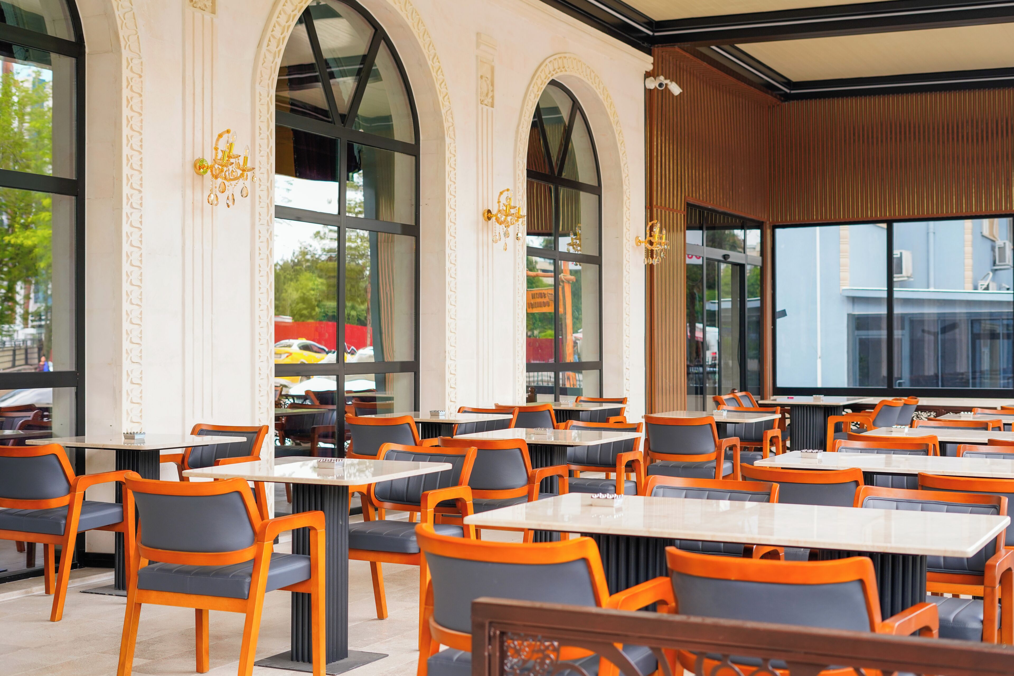 A restaurant with outdoor seating, large windows, and a modern interior design.