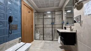 A modern bathroom with a wooden door, a glass shower enclosure, a white bathtub, and a black vanity with a mirror.