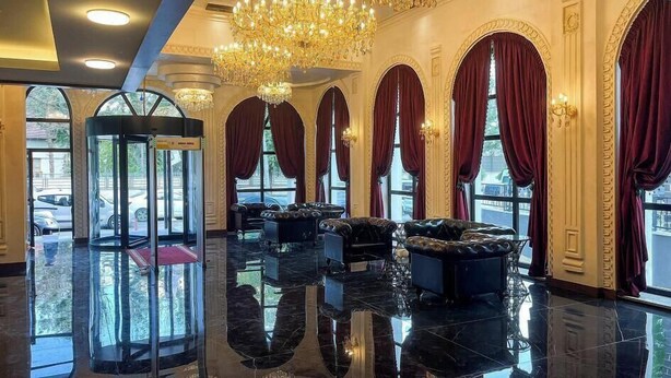 A lobby with a revolving door, marble flooring, and red curtains. - TURİSTİK PALAS OTEL (Diyarbakir)