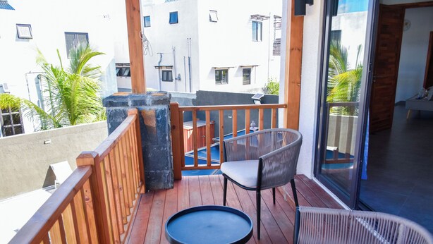 A balcony with wooden railings, a round table, and two wicker chairs. - Fazz Boutique Villa-private pool (Grand Baie)