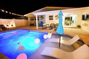 A swimming pool with a swan float and balloons, surrounded by lounge chairs and a covered patio area.