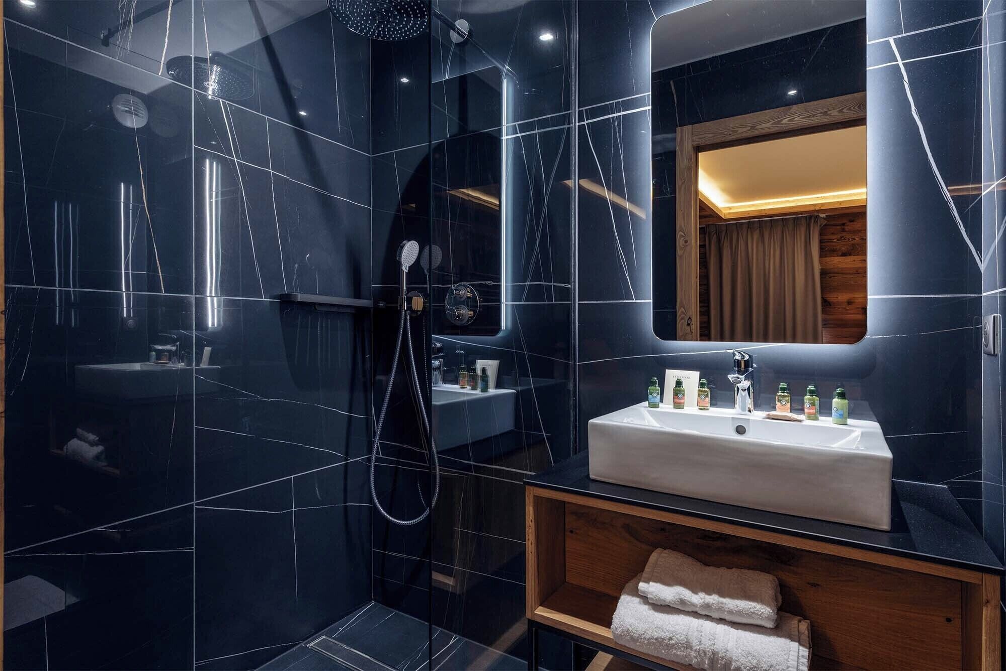 A modern bathroom with a glass-enclosed shower, a white sink, and a wooden vanity.