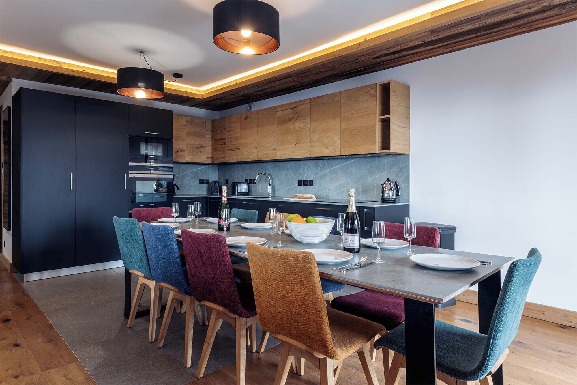 A modern kitchen with dark cabinets, a wooden countertop, and a dining area with a table set for four.