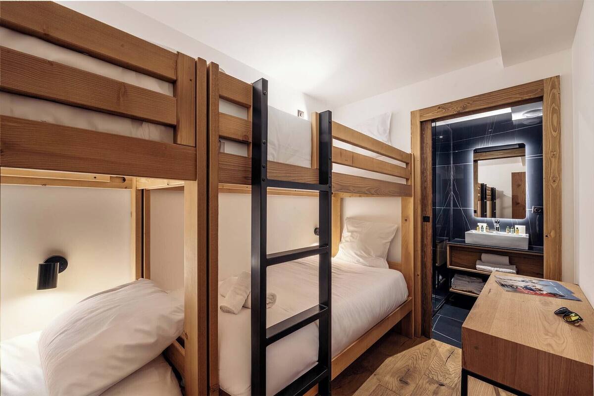 Ein Schlafraum mit Etagenbett, Holzbettgestell, Nachttisch und Spiegel.