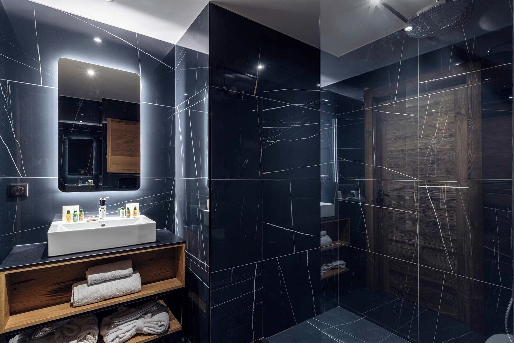 Un baño moderno con un espejo grande, un lavamanos blanco y un tocador de madera.