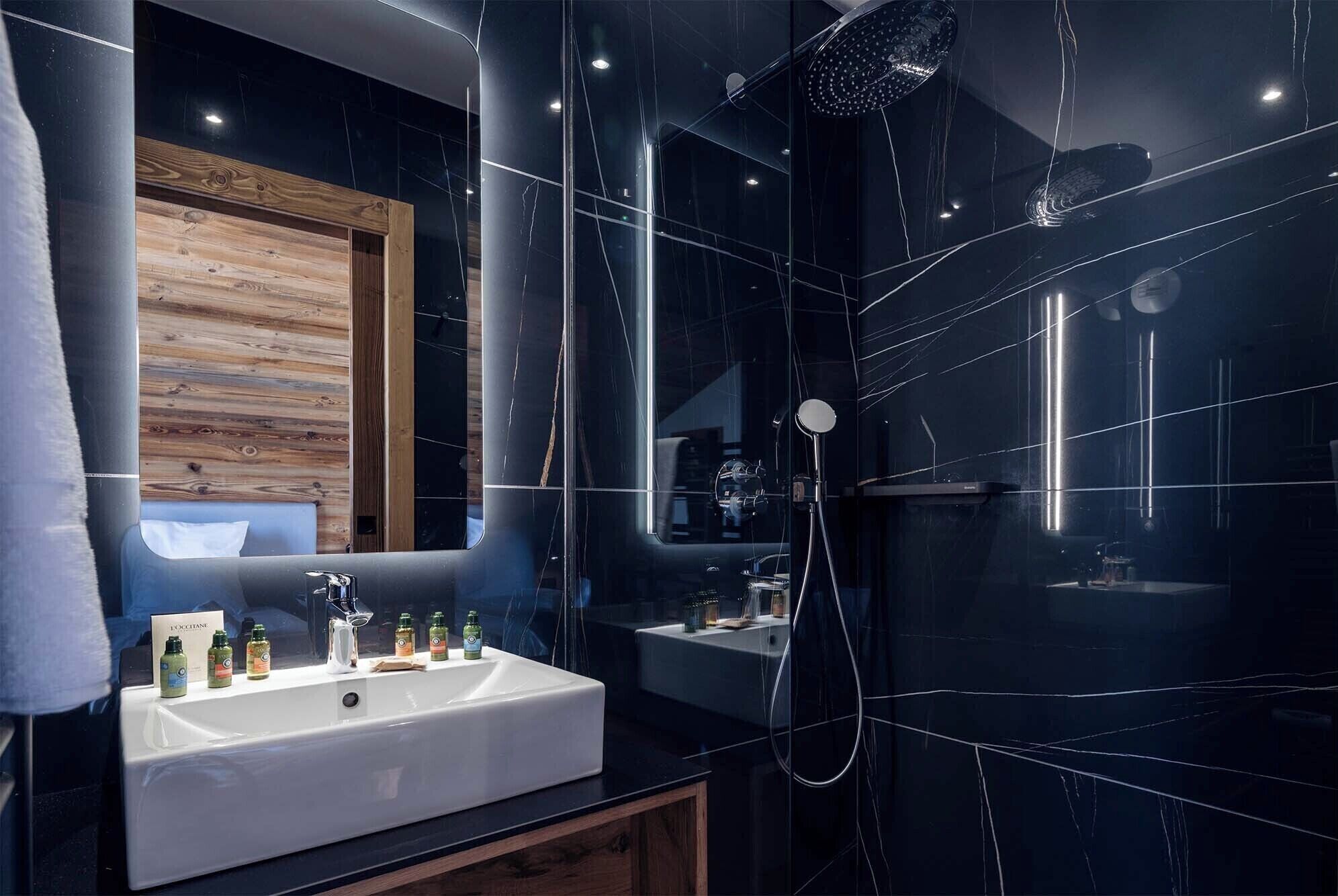 Un baño moderno con un espejo grande, un lavabo blanco y una zona de ducha.