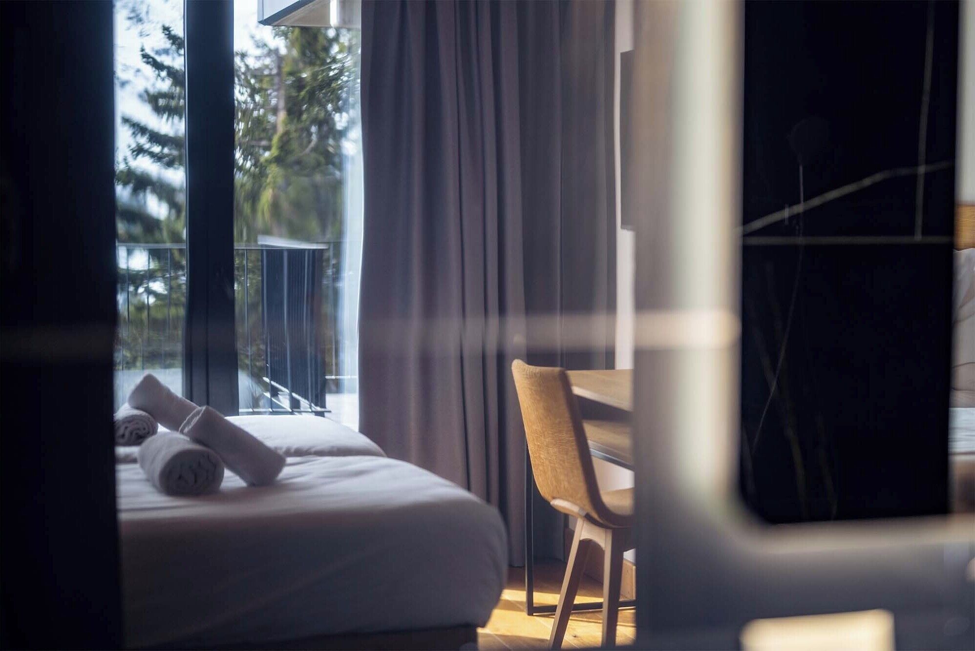 A hotel room with a bed, a chair, and a window with curtains.