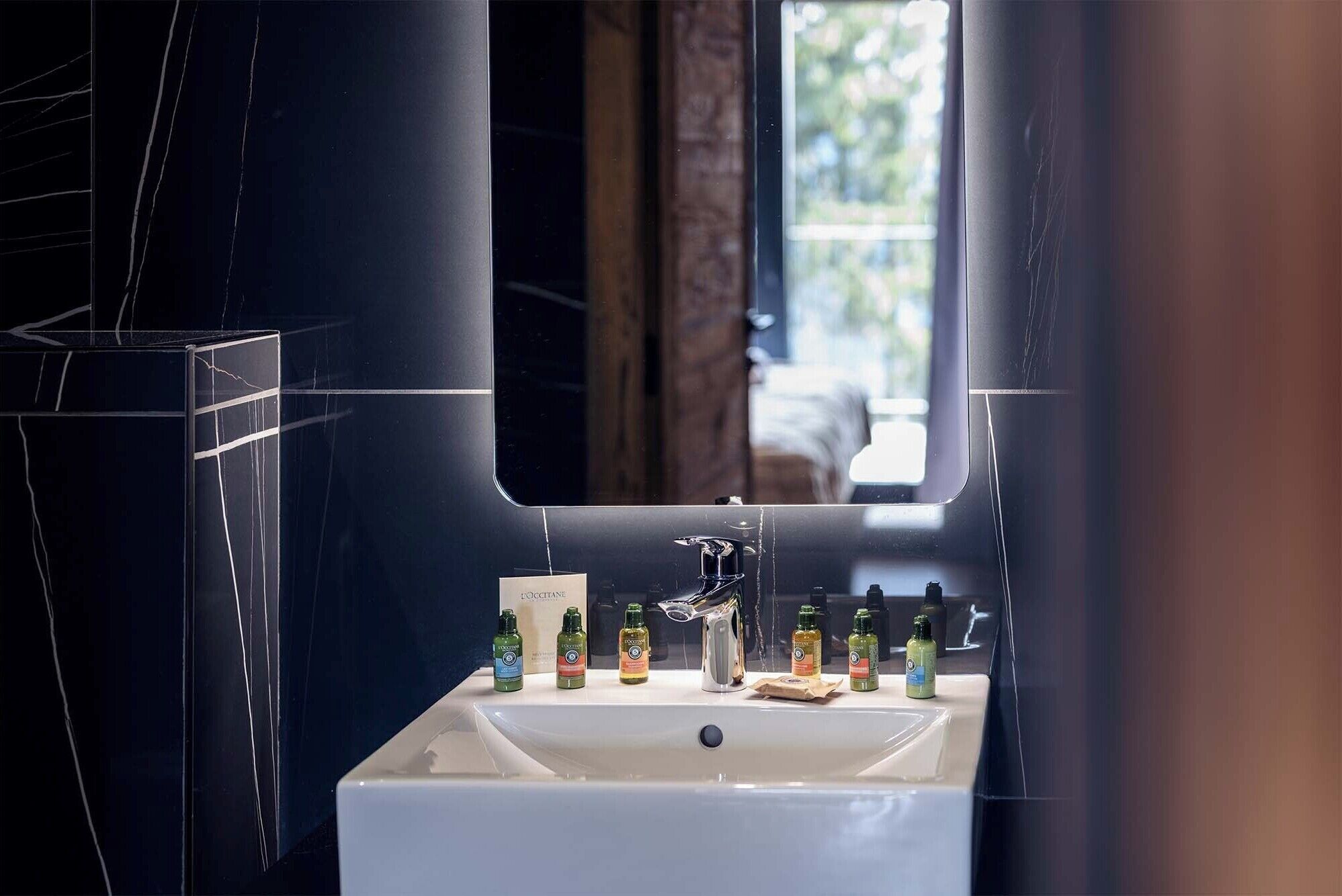 A bathroom with a white sink, a mirror, and toiletries on the counter.