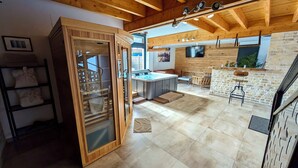 A modern kitchen with a wooden ceiling, a built-in hot tub, and a stone wall. - Loft Terre Jacuzzi and sauna Gravelines (Gravelines)