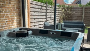 A hot tub with a control panel, a wooden fence, and a view of the sky and buildings. - Loft Terre Jacuzzi and sauna Gravelines (Gravelines)