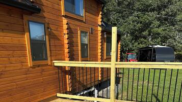 Eine Holzterrasse mit einer Hängematte und einem Holzhaus im Hintergrund.