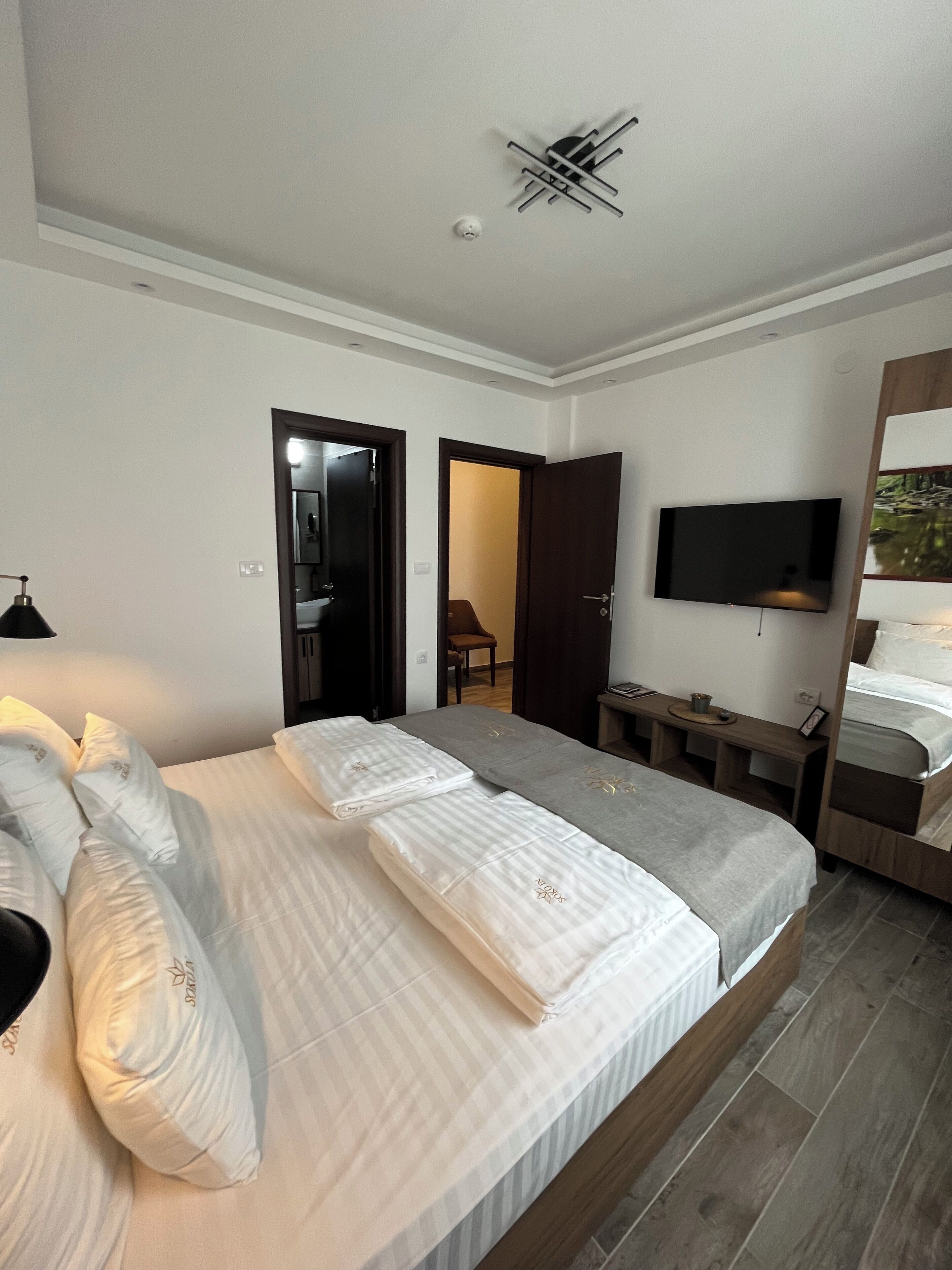 Une chambre à coucher moderne avec un grand lit, un téléviseur fixé au mur et un bureau avec une chaise.