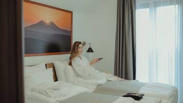 Una habitación de hotel con una cama, una lámpara de noche y un cuadro de un paisaje de montaña.