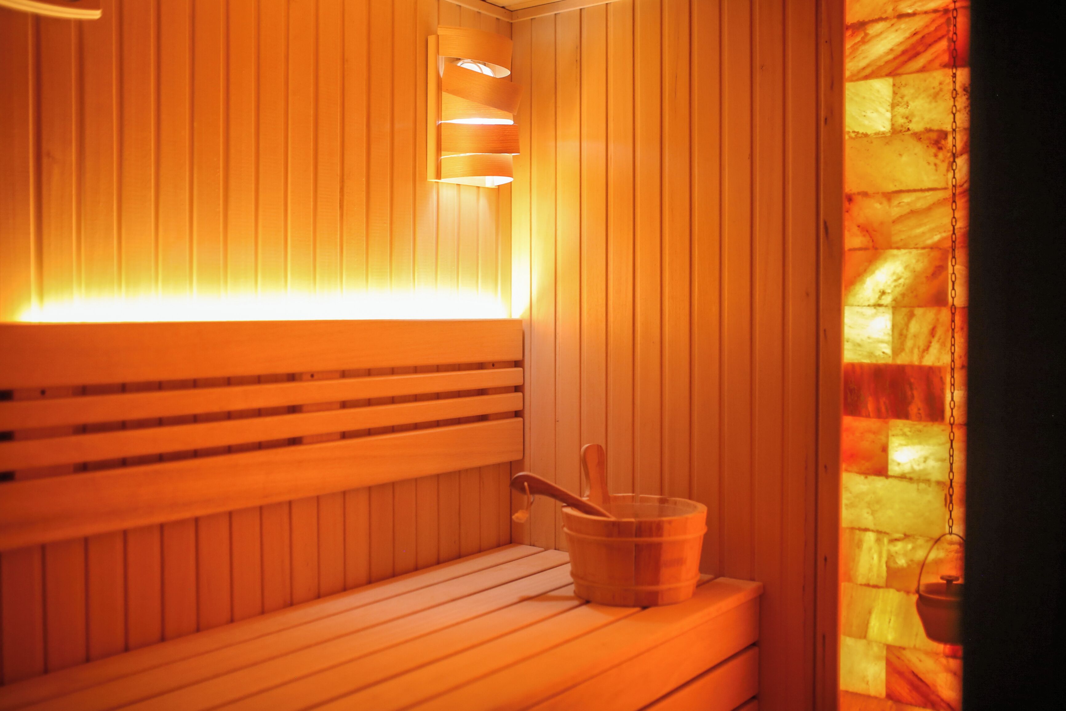 Una sauna con bancos de madera y un balde.