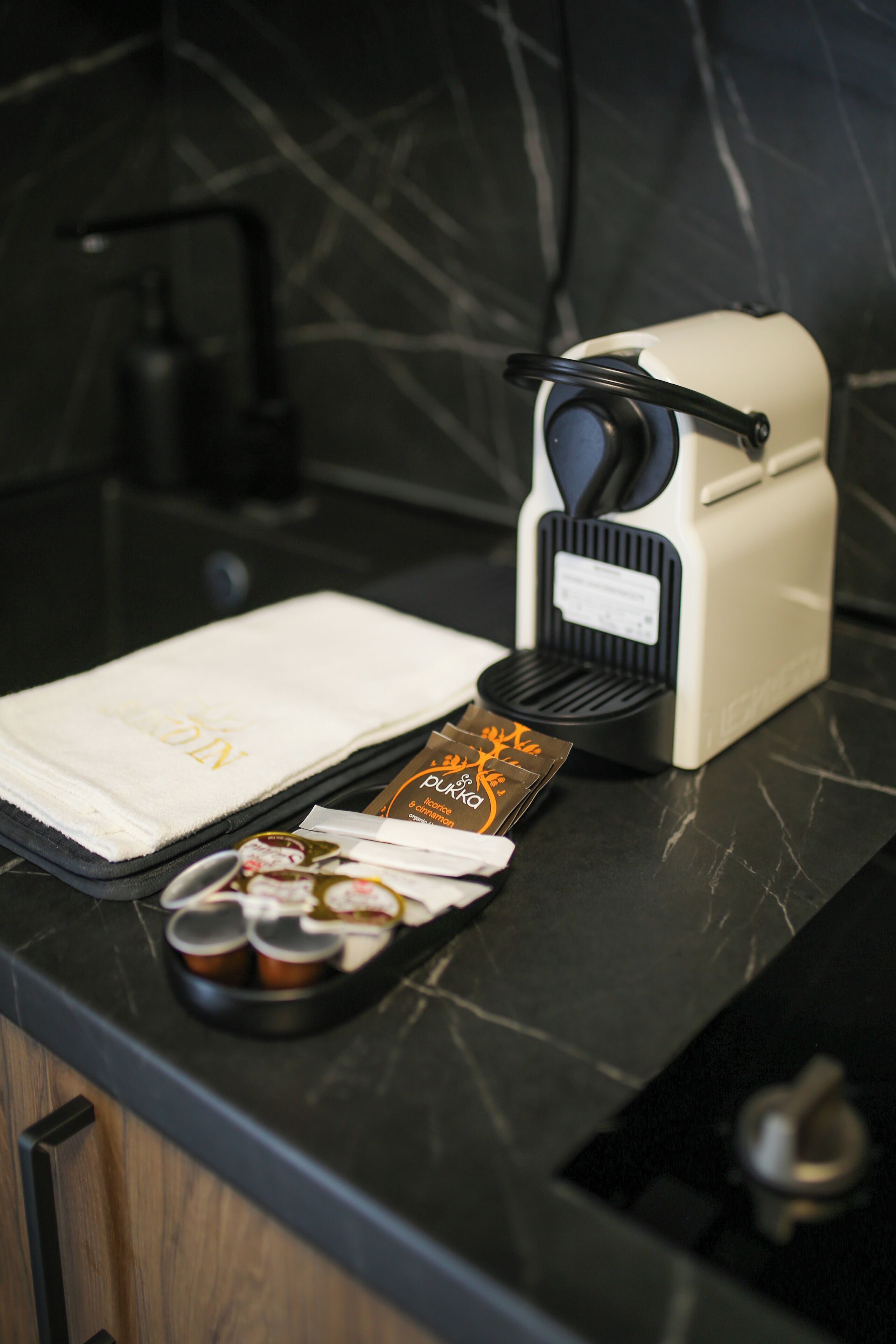 Un comptoir de cuisine avec une machine à café, un plateau rempli de tasses à café et un menu.