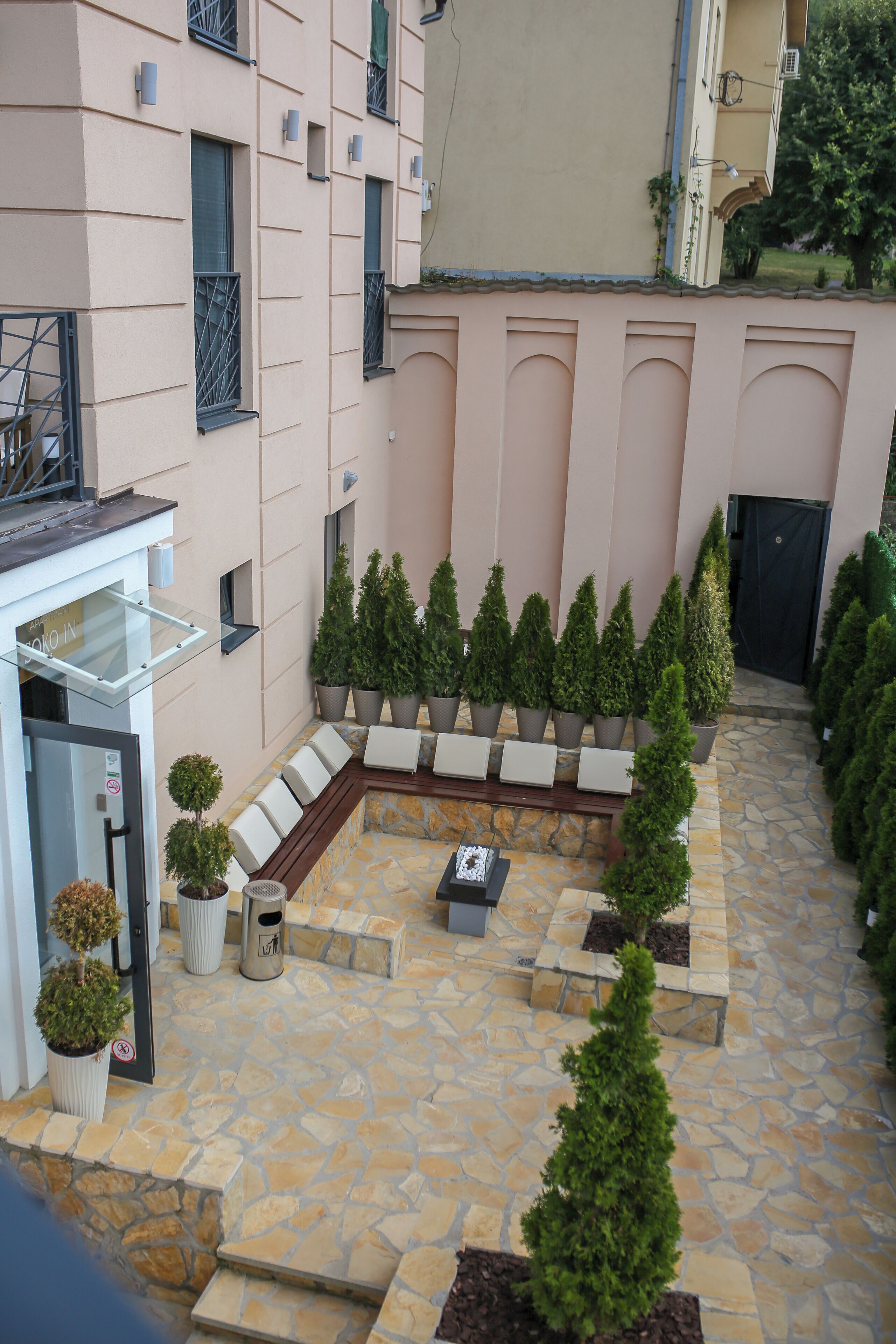 A courtyard with a seating area, potted plants, and a stone floor.