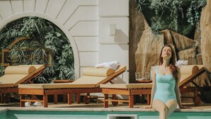 Un área de piscina con sillas de descanso y una pared decorativa.
