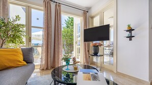 A modern living room with a sofa, a glass coffee table, and a flat-screen TV. - J1 Holiday House Adjacent to Aphrodite Hills - Sea View (Kouklia)