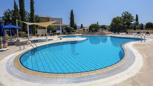 A large, curved swimming pool with a tiled deck and lounge chairs. - J1 Holiday House Adjacent to Aphrodite Hills - Sea View (Kouklia)