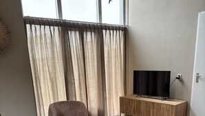 Ein modernes Wohnzimmer mit einer Couch, einem Couchtisch und einem Fernseher auf einem Holzboden.