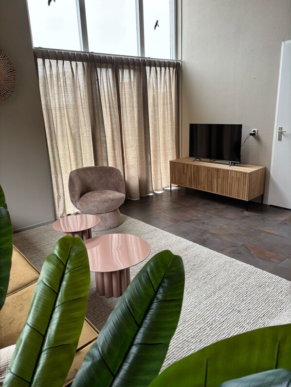 Una sala moderna con un sofá, una mesa de centro y un televisor sobre un soporte de madera.