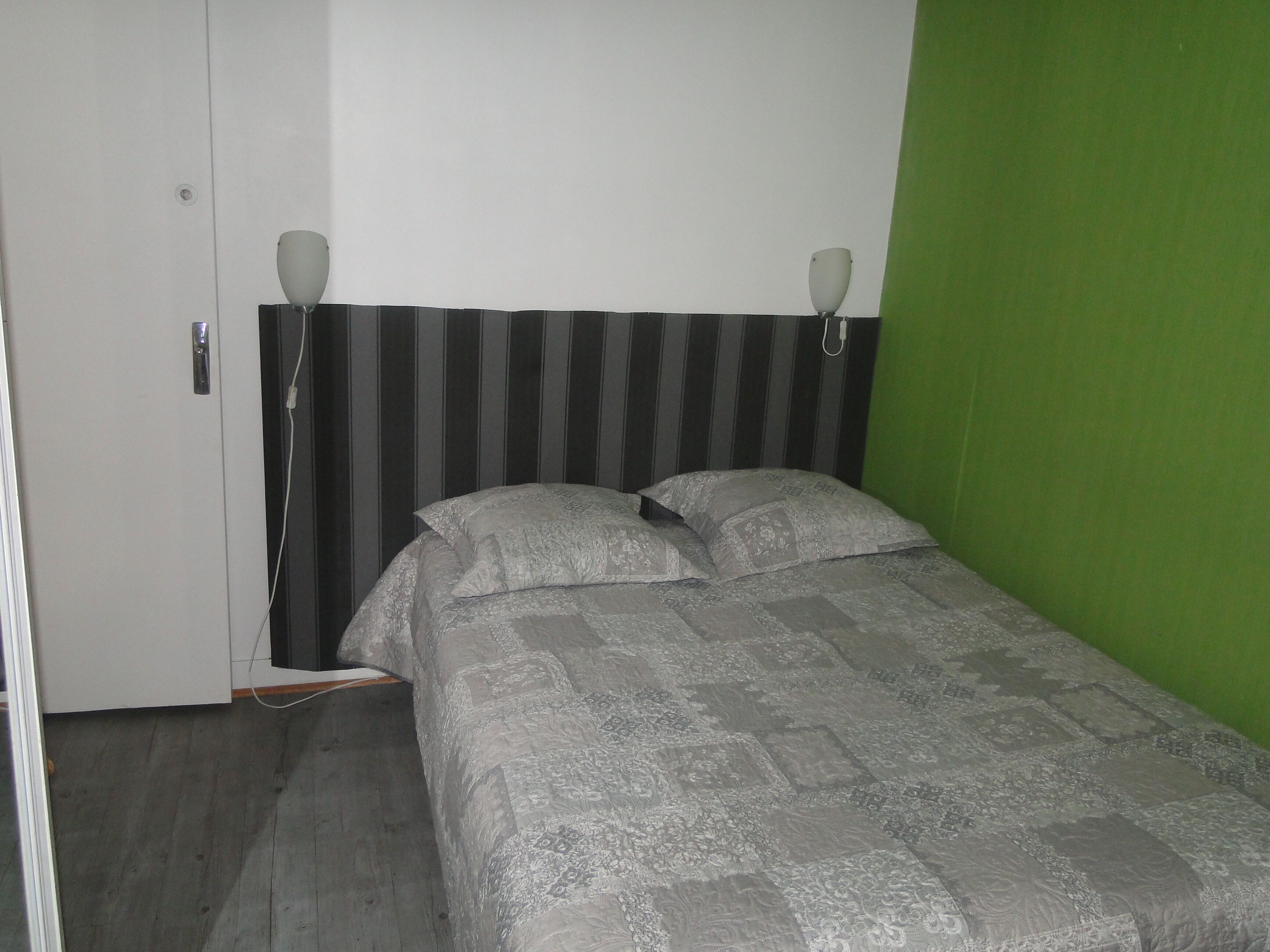 Una cama individual con un edredón estampado, un cabecero a rayas y dos lámparas de noche.