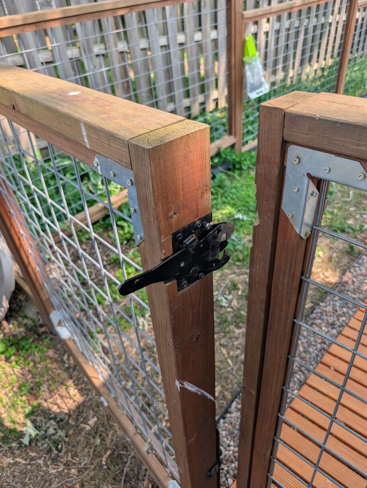 A wooden fence with metal mesh and a black metal latch.