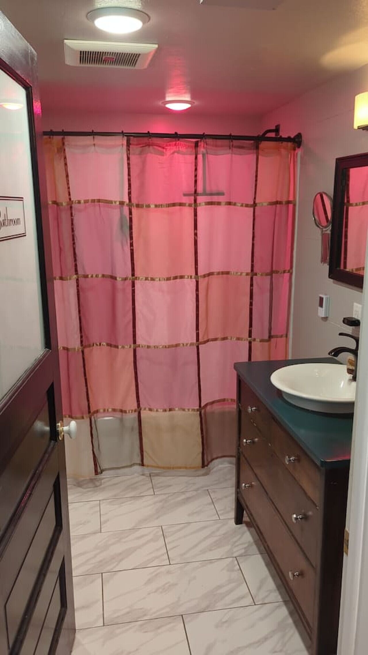 Un baño con cortina de ducha, lavamanos, espejo y retrete.