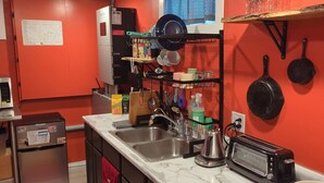 A kitchen with a sink, stove, and microwave. There is a map on the wall and a shelf with dishes.