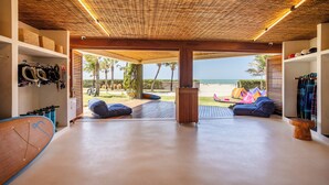 A spacious room with a view of the beach, a surfboard, and a wooden ceiling. - Casa Siará - Preá (Cruz)