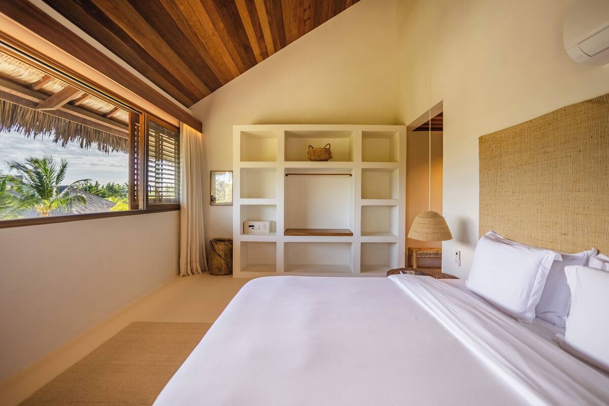 Un dormitorio con una cama grande, una estantería empotrada y vistas a palmeras.