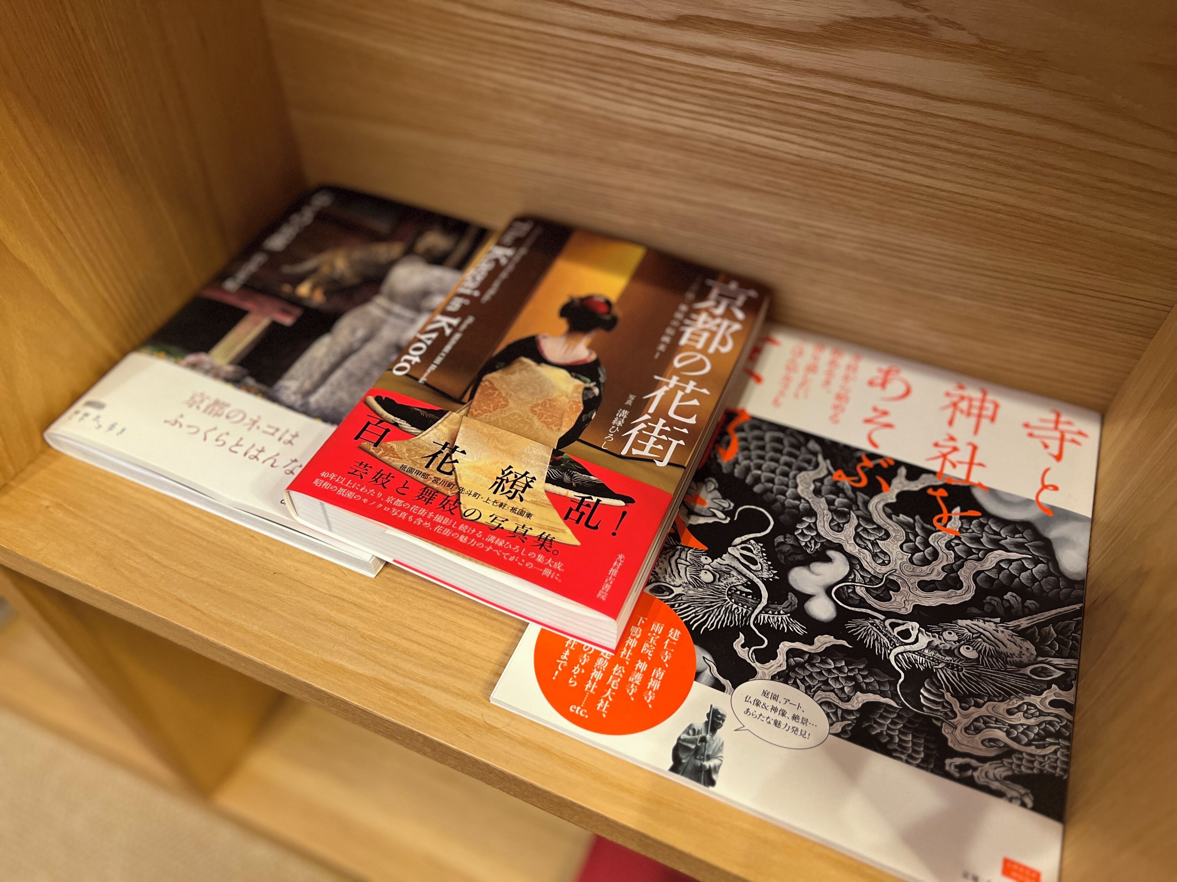 Una estantería de madera con libros, incluyendo un libro rojo con texto en japonés e ilustrado con un dragón negro.