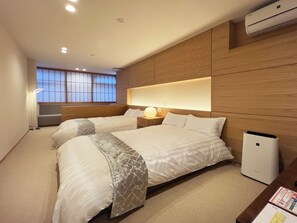 Une chambre d’hôtel avec deux lits, une table de chevet avec une lampe, une fenêtre donnant sur un beau paysage et un appareil de climatisation.