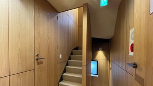 Un intérieur en bois avec un escalier recouvert de moquette et un détecteur d’incendie fixé au mur.